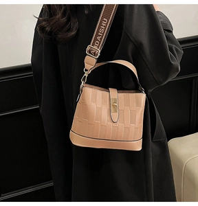 Close-up of khaki bucket bag showing embossed checkered texture and gold twist-lock