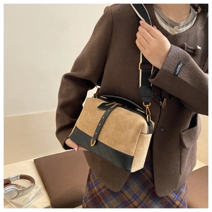 Detail of suede quilted crossbody bag with two-tone stitching and wide shoulder strap