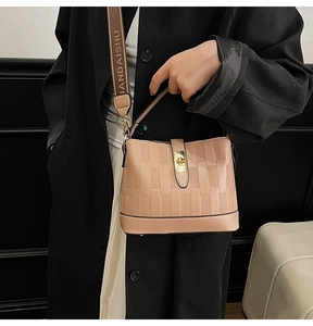 Detail of quilted beige bucket bag featuring gold twist-lock and branded woven strap