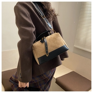 Detailed side view of quilted faux suede pillow bag with contrast strap worn by model