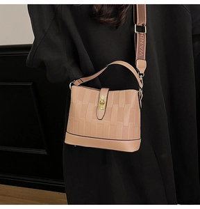 Close-up of khaki woven texture bucket bag with gold twist lock and wide logo strap