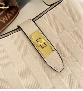 Close-up of off-white leather bucket bag with cross-grain texture and gold clasp