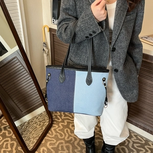 Large denim patchwork tote bag with blue contrast panels and slim black shoulder straps