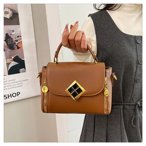 Détail d'un sac à main marron en cuir grainé avec fermoir doré et détails de fermeture éclair