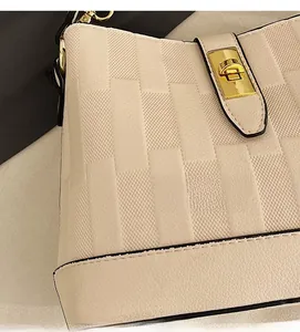 Close-up of beige bucket bag showing woven leather texture and gold rectangular clasp