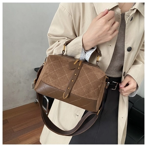 Detail of brown suede crossbody bag showing quilted pattern and metal studs on the side