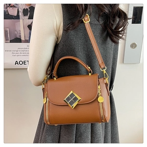 Vue détaillée du sac en cuir marron à motif litchi avec boucle dorée et poignée