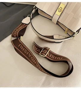 Detailed close-up of cream textured leather bucket bag with wide brown woven strap