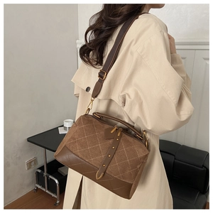 Brown quilted suede boston bag with gold hardware worn with a beige trench coat