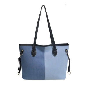 Minimalist denim patchwork tote bag with black faux leather straps and metal rivets