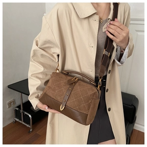 Detailed side view of a brown suede crossbody bag with vintage quilted patterns and studs