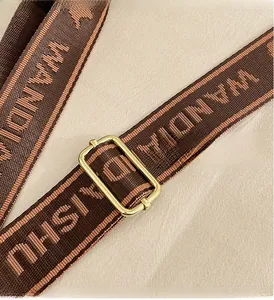 Macro detail of brown woven jacquard shoulder strap with golden metal adjustment buckle