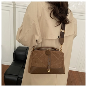 Detail of retro brown suede pillow bag with diamond stitching and adjustable woven strap