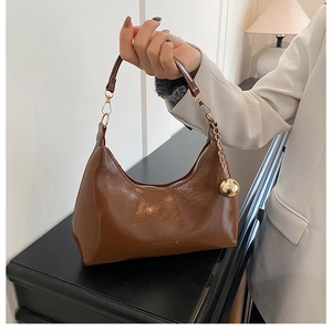 Détail d'un sac à main en cuir verni avec un grand pendentif boule dorée miroir