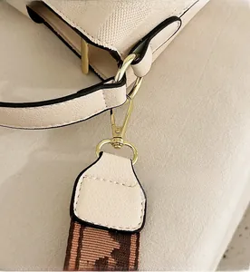 Detail of light beige lychee leather bag with gold hook and jacquard woven strap
