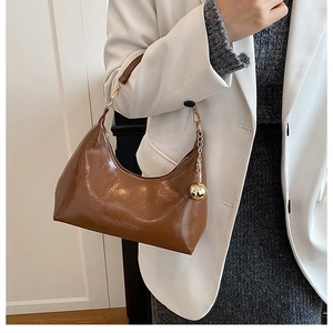 Détail du sac bandoulière en cuir verni marron avec chaîne dorée et gaufrage fashion