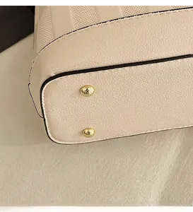 Detail of beige pebbled leather bag base with protective gold metal rivets