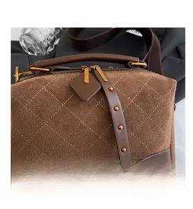Detail of brown faux suede handbag showing diamond quilting and gold stud accents