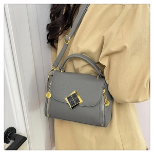 Sac à main gris foncé avec boucle dorée et bandoulière réglable, porté par un mannequin