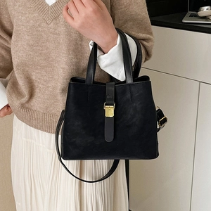 Black vintage textured bucket bag with golden buckle and adjustable strap on a model