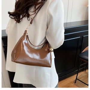 Détail d'un sac hobo en cuir verni marron avec ferrures dorées et logo FASHION embossé