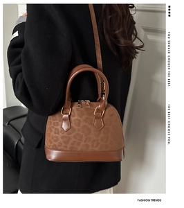 Close-up of vintage leopard print shell bag with golden hardware and adjustable strap