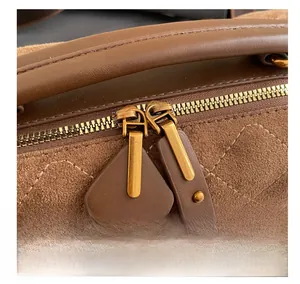Detailed macro view of smooth dual golden metal zippers on brown suede quilted handbag