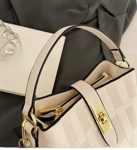 Macro view of beige bucket bag featuring woven texture and gold twist-lock hardware