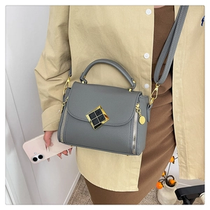 Détail du sac à main gris en cuir litchi avec boucle en métal noir à bordure dorée et anse