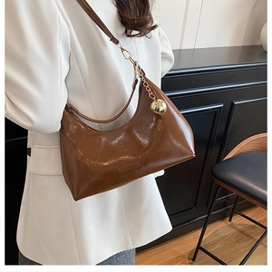 Détail du sac hobo en cuir verni caramel avec gaufrage FASHION et breloque dorée
