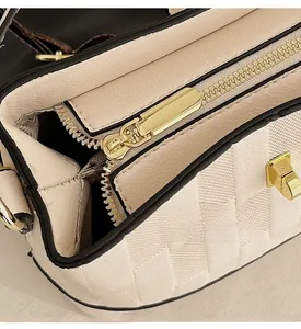 Detail of smooth gold zipper slider and quilted leather texture on a beige bucket bag