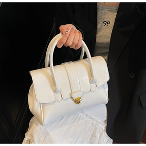 Detail of white minimalist handbag featuring textured faux leather and gold triangular lock