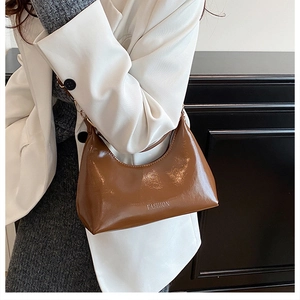 Gros plan détaillé d'un sac hobo en cuir verni marron avec détails dorés et imprimés