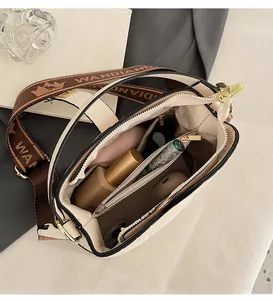 Interior view of off-white bucket bag showing spacious compartments and wide woven strap