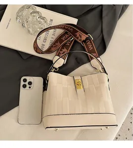Beige bucket bag with geometric texture, gold twist lock, and jacquard strap next to accessories