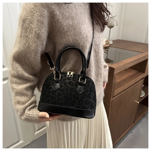 Detail view of stylish leopard print shell bag with golden zippers and leather texture