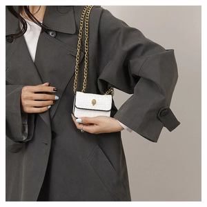 Détail du cuir à motif crocodile blanc sur mini sac avec boucle de tête d'aigle dorée