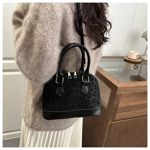 Detail of leopard print shell bag with black leather trim and golden hardware zippers