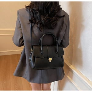 Close-up of black PU leather briefcase featuring golden metal clasp and twin top handles