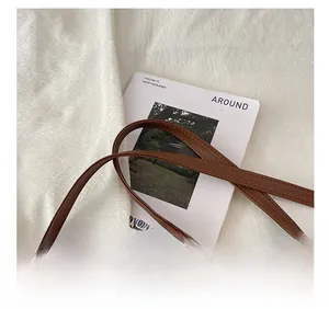 Détail de la bandoulière réglable en cuir marron motif litchi avec boucle en métal doré