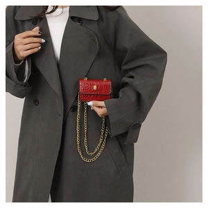 Détail du mini sac rouge texture crocodile avec boucle tête de mort et chaîne dorée
