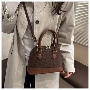 Leopard print shell handbag with leather trim shown on a model with khaki coat