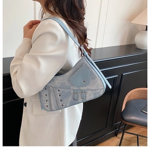 Close-up of light blue saddle bag with metallic grommets and vintage strap details
