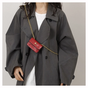 Détail du mini sac rouge à motif crocodile avec chaîne dorée et tête d'aigle en métal