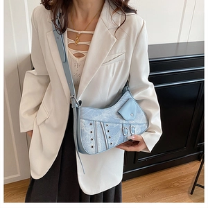 Close-up of light blue denim shoulder bag featuring moto-style zippers and metal eyelets