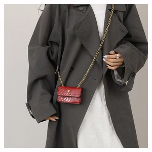 Détail du mini sac rouge à effet croco avec boucle tête d'aigle dorée sur un mannequin