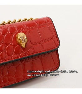Détail du mini sac rouge effet croco avec tête d'aigle dorée et bandoulière chaîne