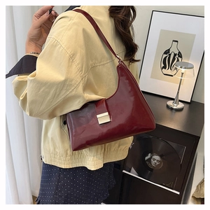 Detail of burgundy glossy patent leather crescent bag with silver metallic clasp closure