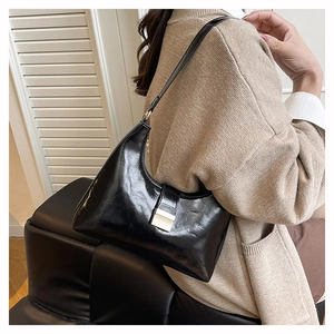 Polished black leather crescent shoulder bag with golden metallic buckle on model