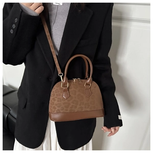 Detail of leopard print shell bag with brown leather handles and golden zippers